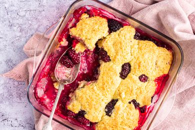 Overhead view of easy blackberry cobbler in a baking dish with a spoon set where a serving was removed.