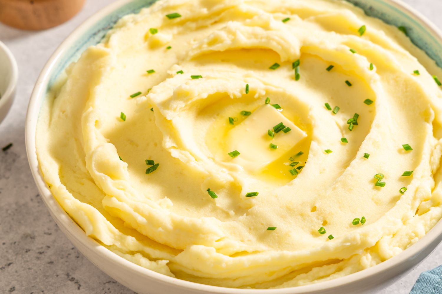 Bowl of mashed potatoes topped with butter and chives