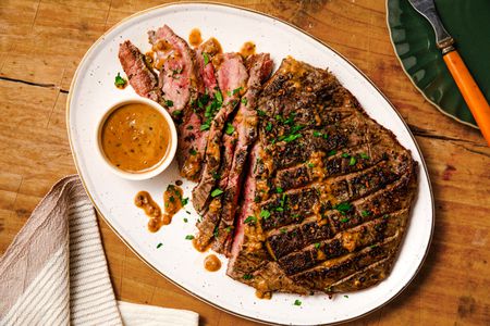 Overhead view of easy steak au poivre on a platter on a wooden tabletop