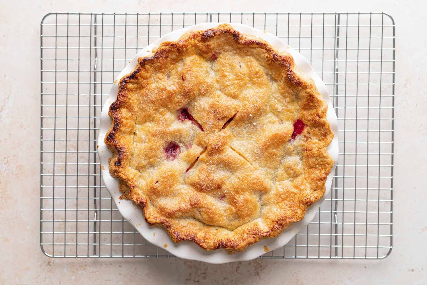 A stone fruit and berry pie cooling on a rack.