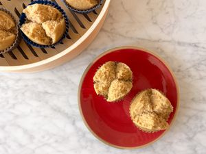 Overhead photo of two longevity cakes on a red plate with a bamboo steamer of steamed longevity cakes peeking in