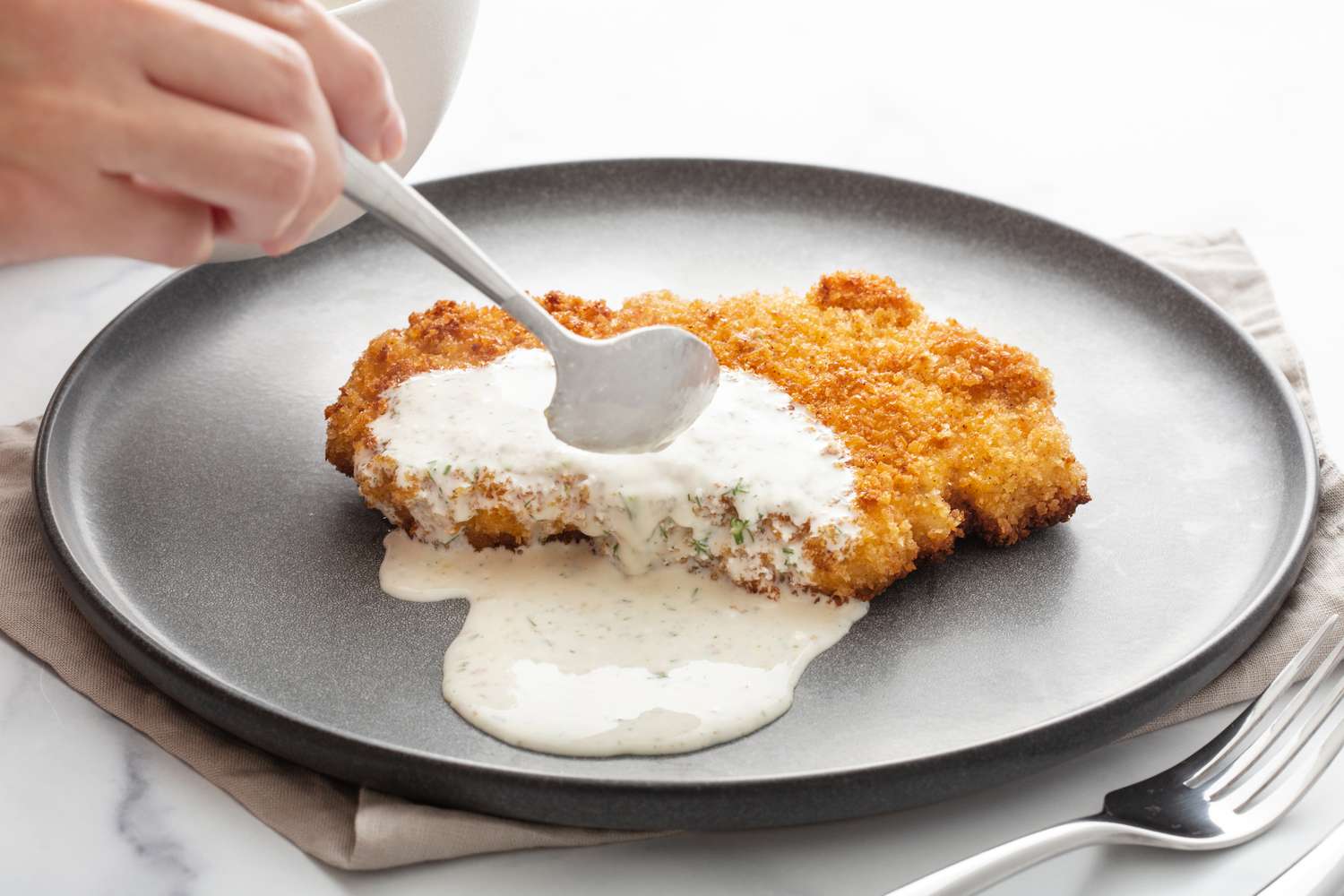 Topping pork schnitzel with sauce on a plate.