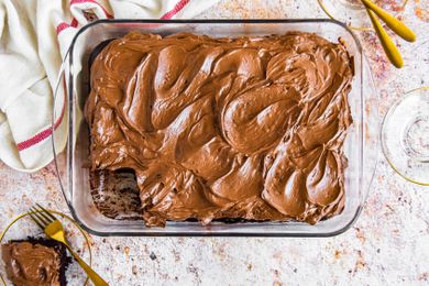 Chocolate Mayonnaise Sheet Cake in a Baking Pan, Surrounded by Small Plates, Utensils, and One Small Plate with a Slice of Cake