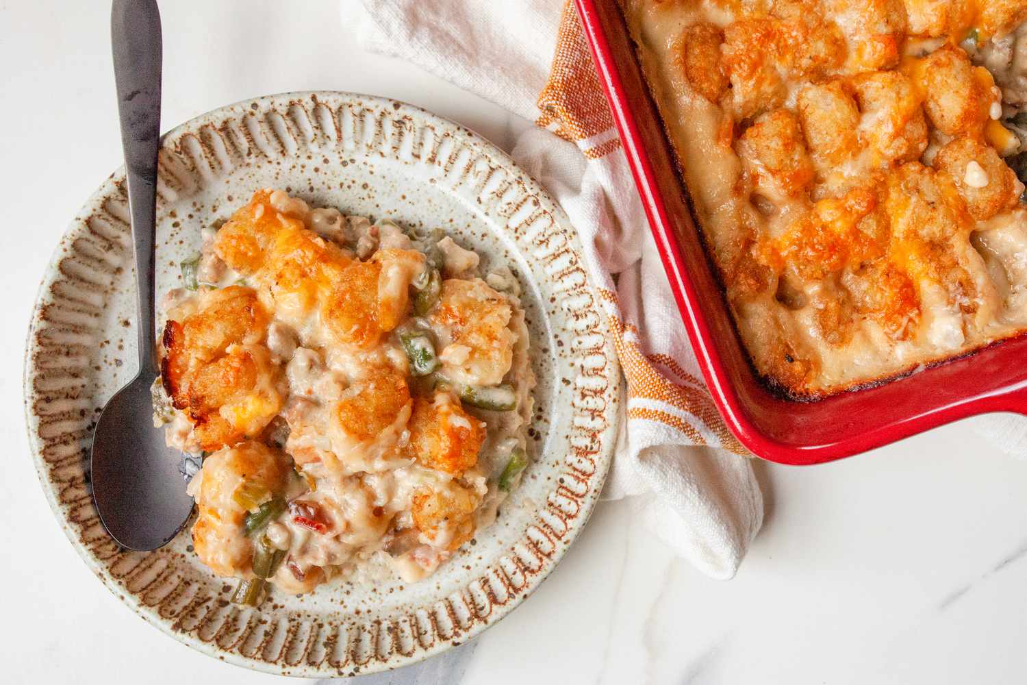 A plate of hotdish next to the baking dish