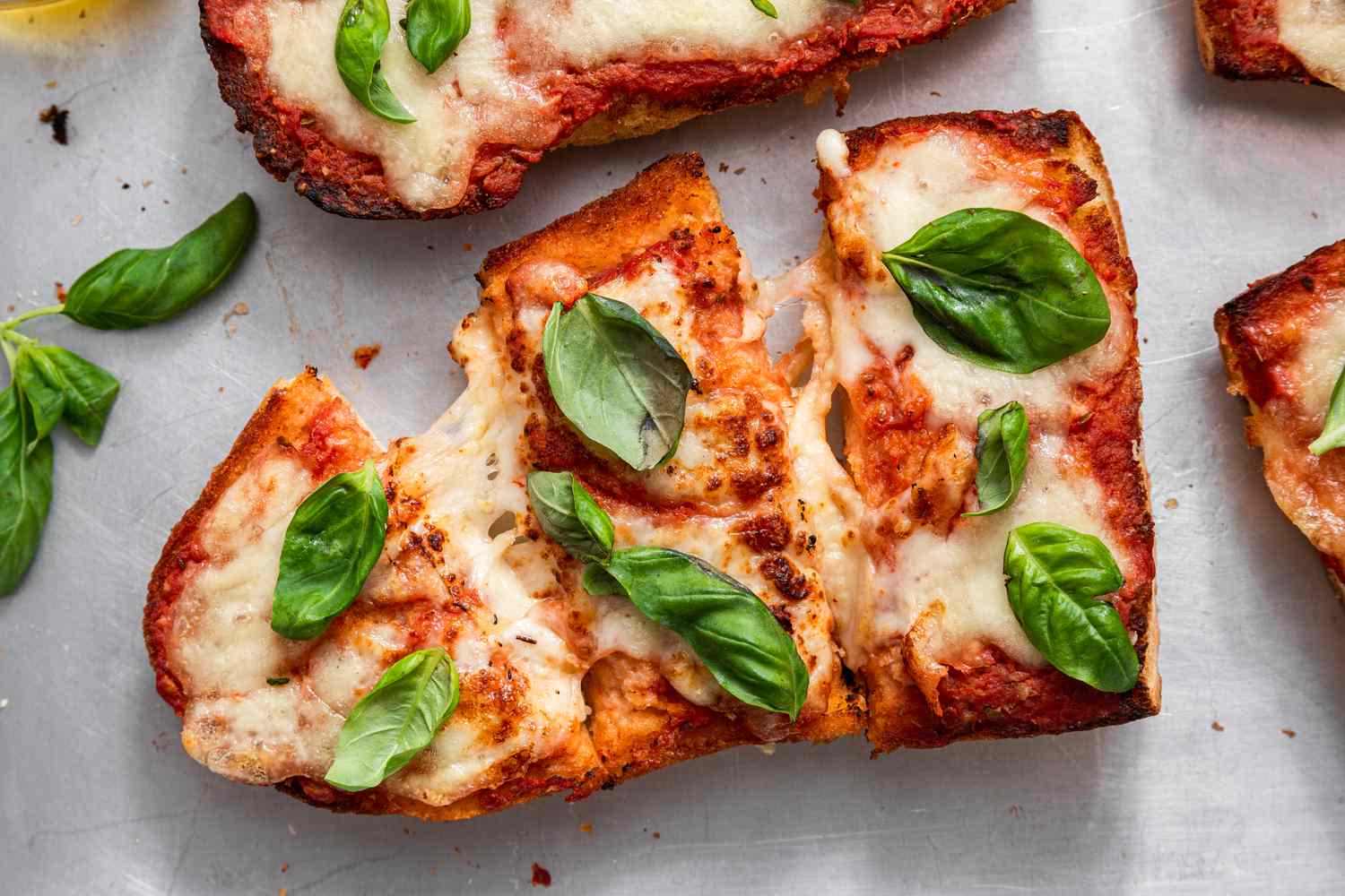 A Sliced French Bread Pizza Topped With Fresh Basil