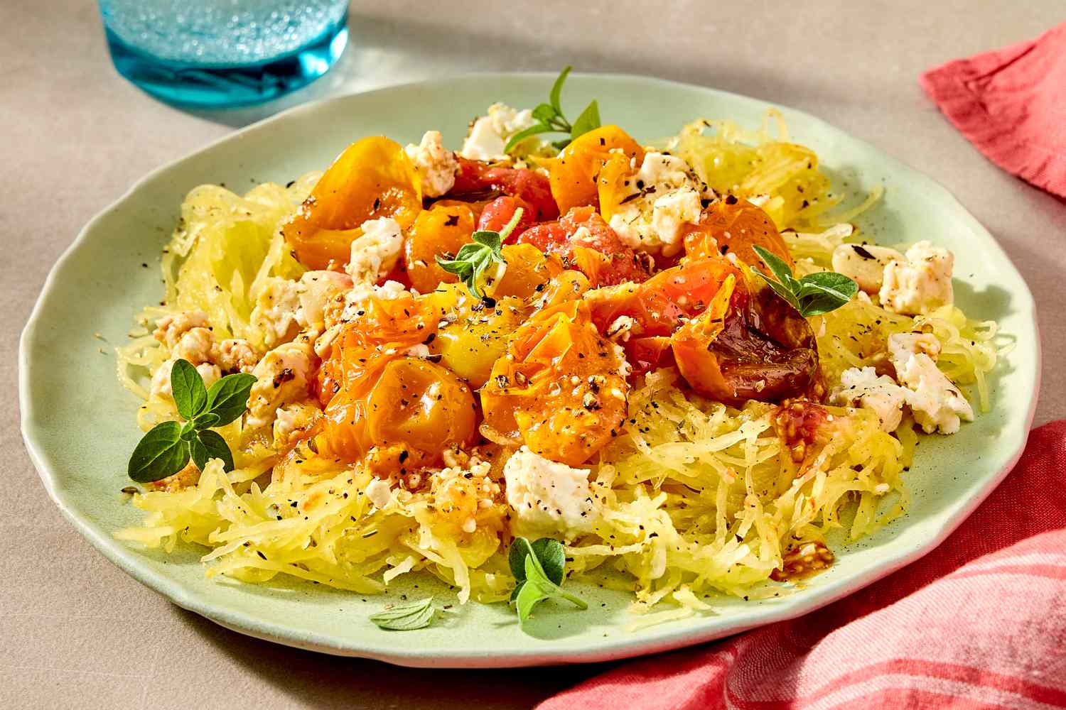Side view of a plate with spaghetti squash topped with feta and cherry tomatoes, 