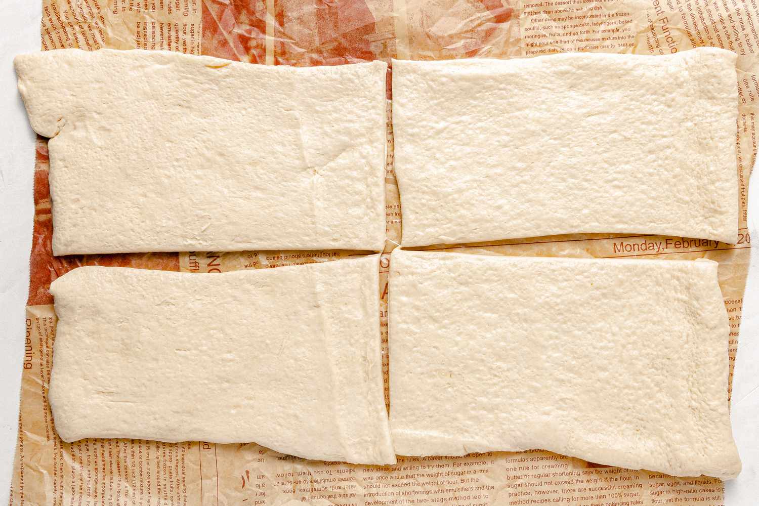 Four Pieces of Crescent Dough on Parchment for Sausage Ppang Recipe