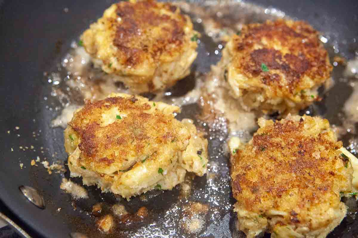 crab cakes frying in pan