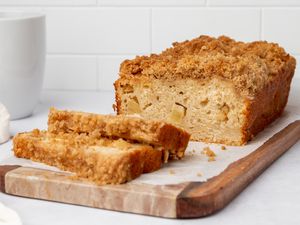 A loaf of homemade apple bread with a few slices cut and laid in front of the loaf.