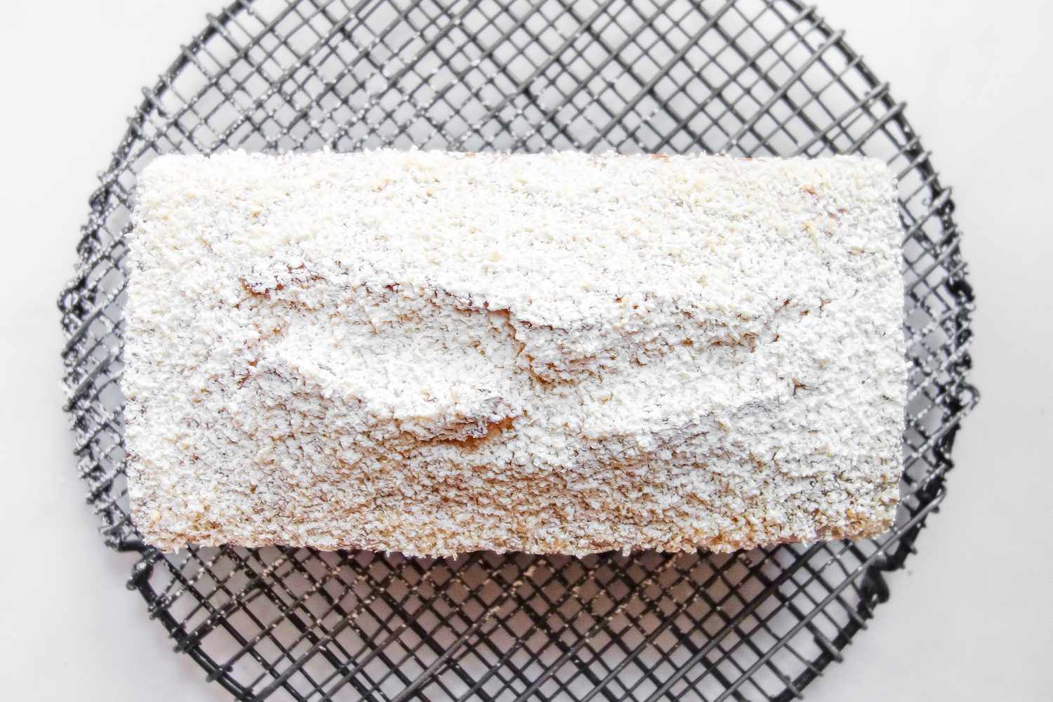 coconut pound cake covered with shredded coconut and powdered sugar
