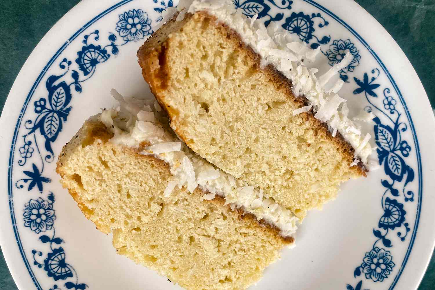 Overhead view of a slice of coconut cake on a white plate with blue decorative detail