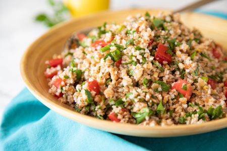 Side view of a tabbouleh salad in a tan bowl.