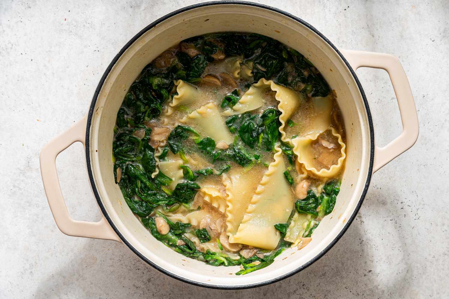 spinach and chicken added to dutch oven for white chicken lasagna soup recipe