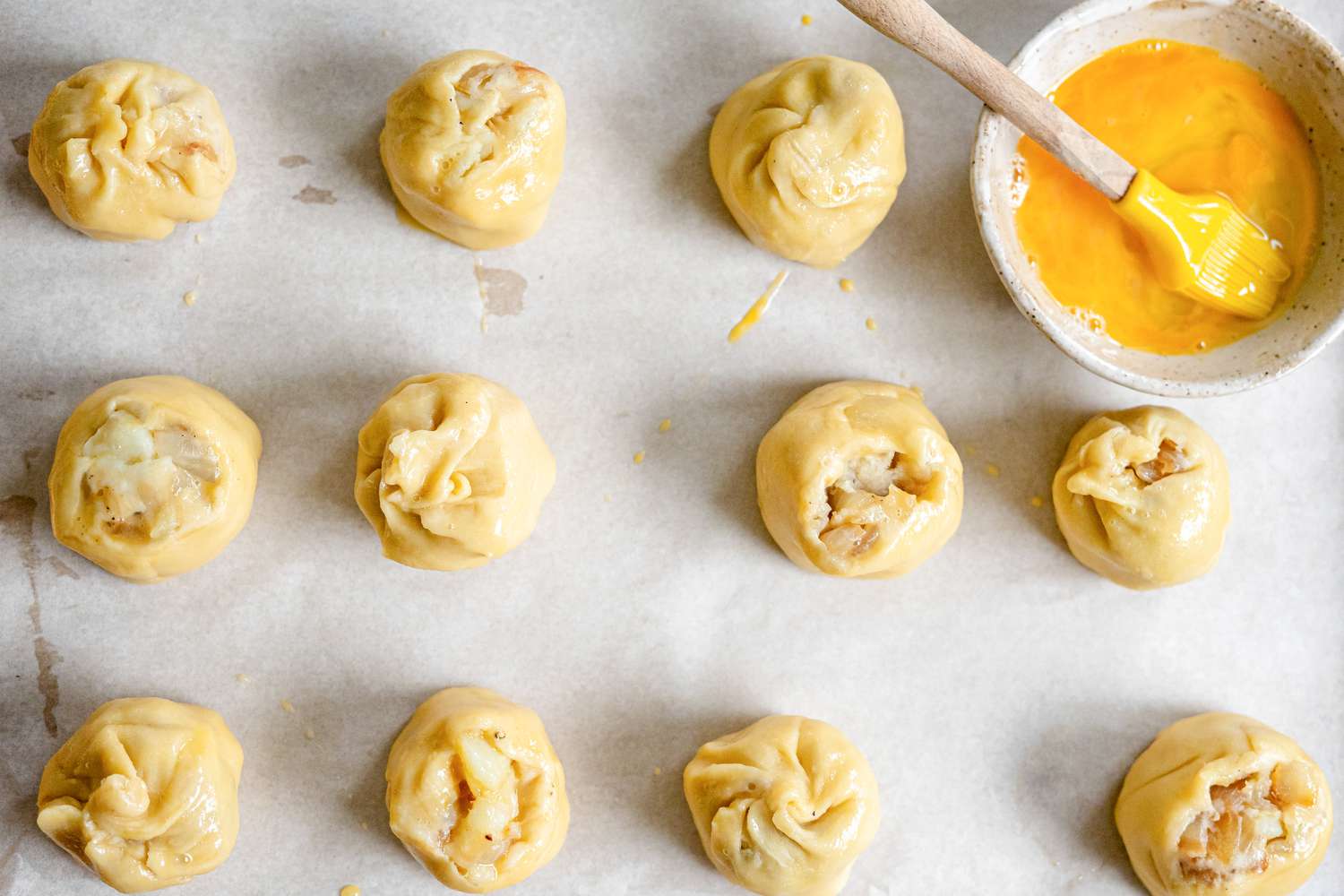Potato Knishes on a Tray with a Bowl of Egg Wash