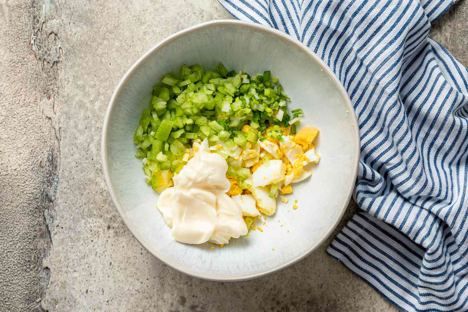 Mixing egg salad ingredients in a bowl to make Egg Salad Sandwiches