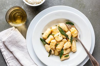 Homemade Potato Gnocchi with sage and brown butter sauce in a plate at a table