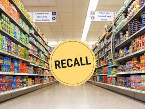 Supermarket aisle with canned goods a large yellow recall sign in the center