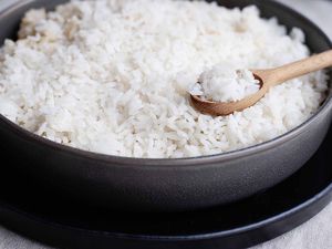 Perfect white rice in a metal pan with a wooden spoon full of cooked white rice.