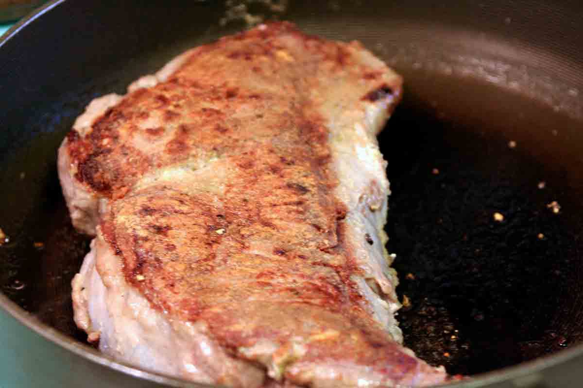 Steak being seared on both sides in a skillet