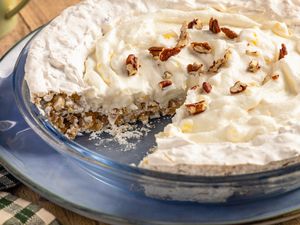 A cream pie with nuts in a blue dish one slice removed