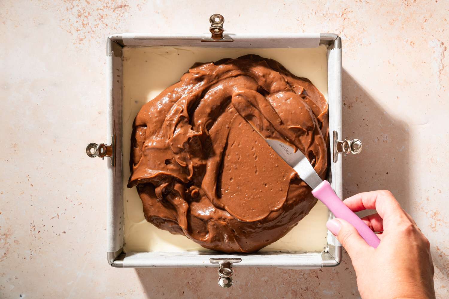 Overhead view of spreading the pudding mixture over the cream cheese layer for Chocolate Delight recipe