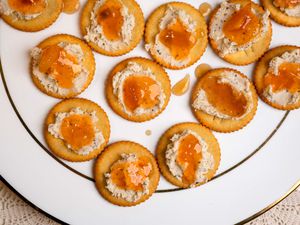 Overhead view of a white plate of Ritz crackers topped with Boursin cheese and mango chutney (Ami's 3-Ingredient Appetizer)