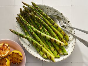 Platter of grilled asparagus with small plate of grilled lemons