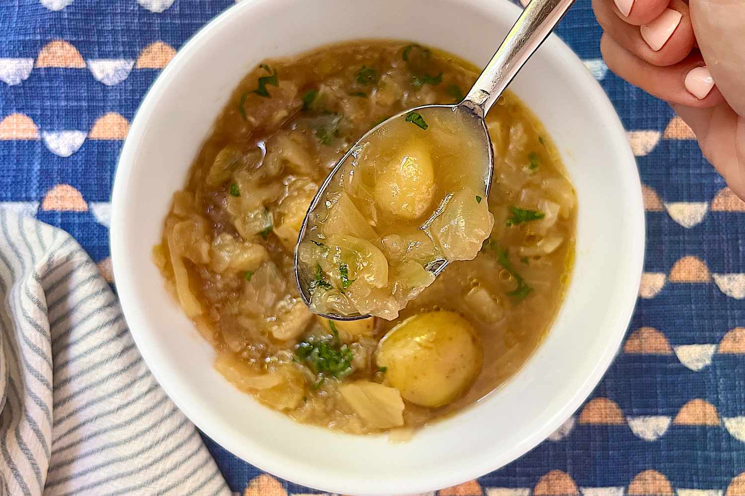 4-Ingredient Cabbage and Potato Soup in a bowl, hand with a spoonful
