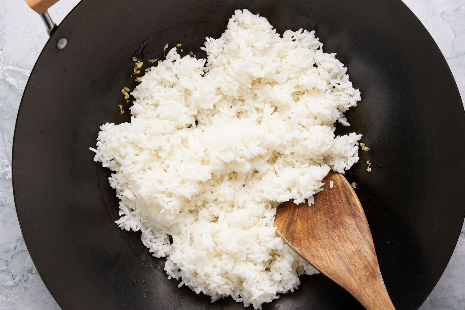 Rice added to wok with minced garlic for Sinangag na Kanin (Garlic Fried Rice) recipe