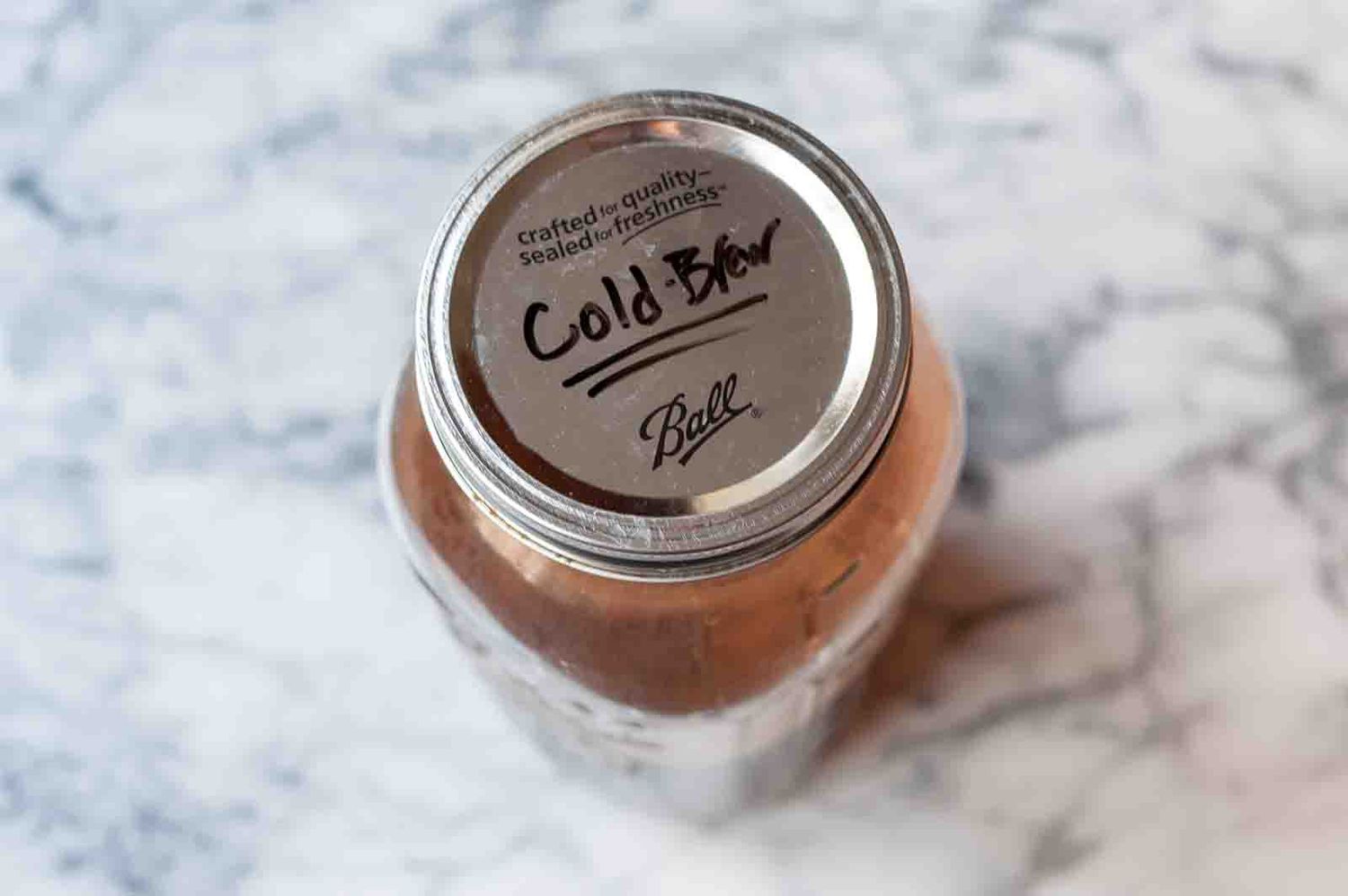A glass jar with a lid that has the words "cold brew" written on top of it 