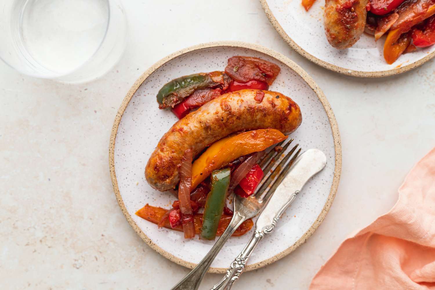 A plate of crockpot sausage and peppers with a fork.
