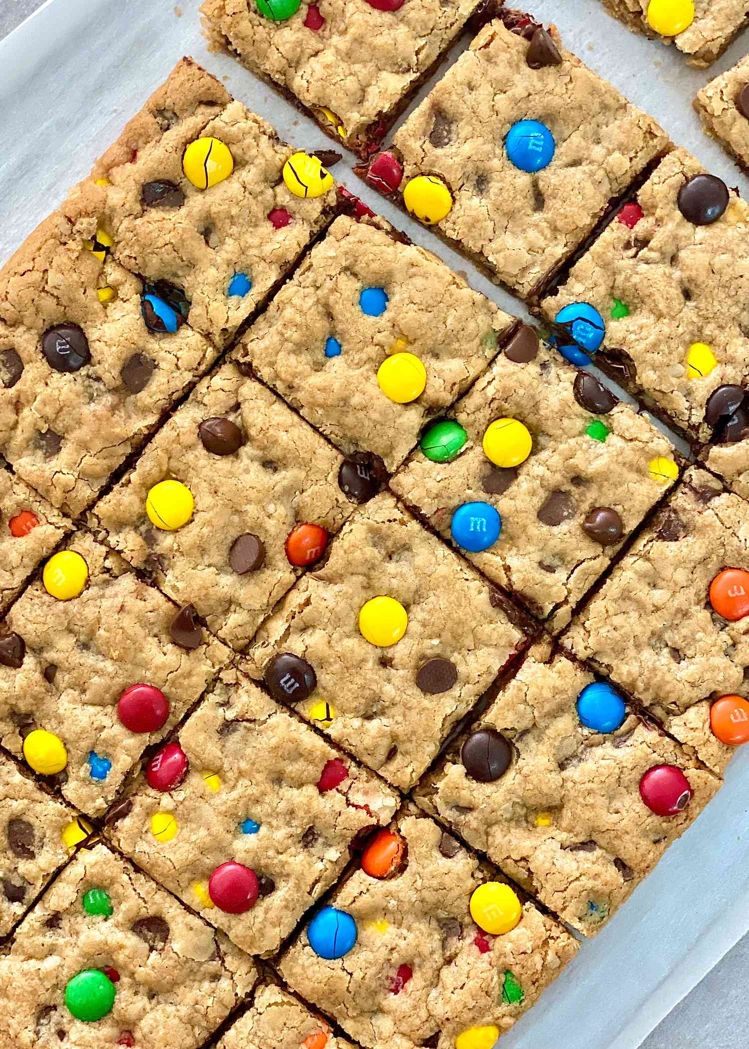 The BEST GF Monster Cookie Recipe sliced into squares and set on parchment paper.