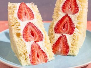 Two slices of strawberry and cream fruit sandwich on a plate