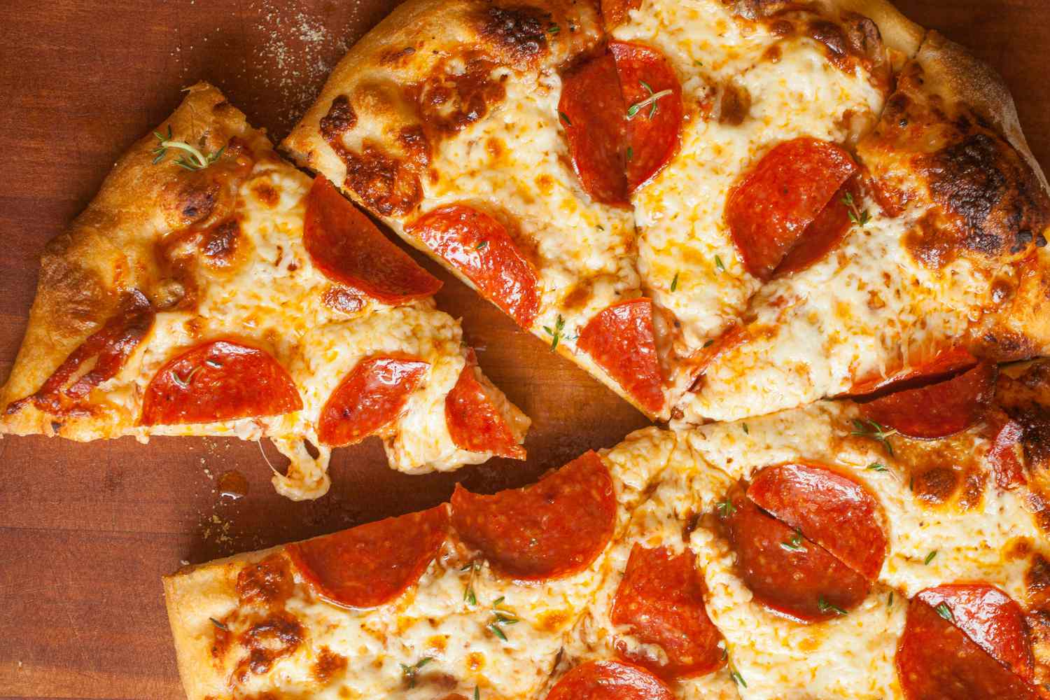 A sliced pepperoni pizza on a wooden counter
