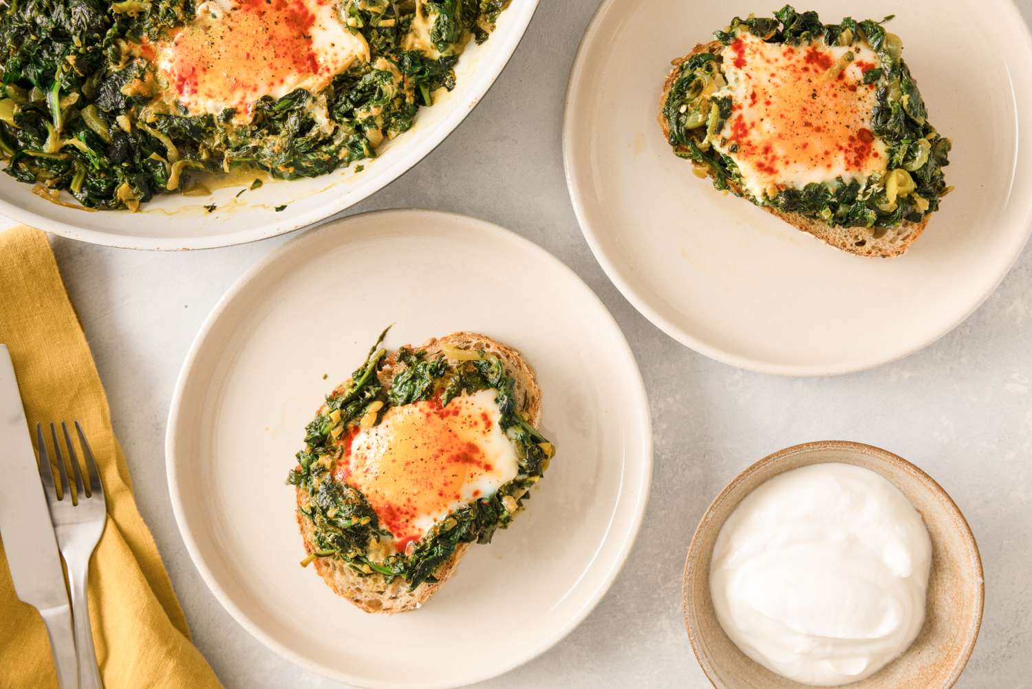 Prepared Nargesi or Persianstyle spinach dish with eggs served on plates with yogurt on the side