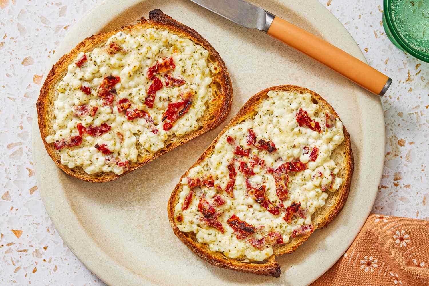 Two pieces of toast topped with cottage cheese and sundried tomatoes on a plate