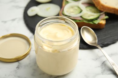 Mayonnaise in a jar with the lid of and a spoon on the side
