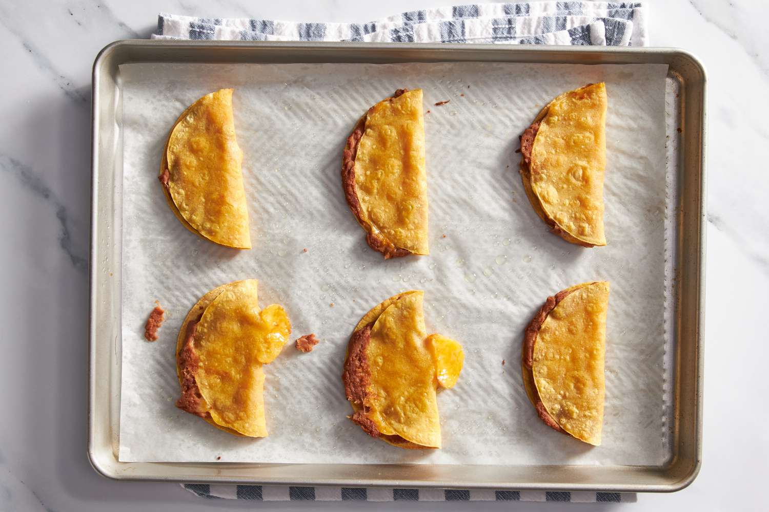 Cheesy baked tacos on a baking sheet after third bake for cheesy baked taco recipe