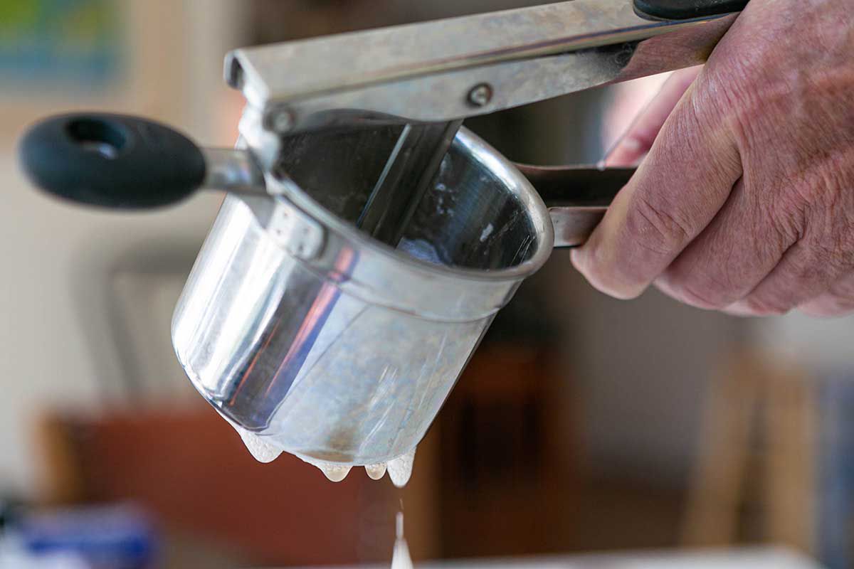 Moisture being squeezed out of shaved potatoes in a ricer 