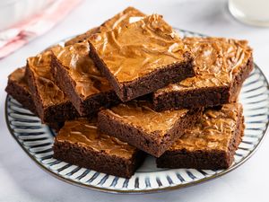 Angle view of a brown and white plate on a marble countertop with a stack of brownies cut into squares