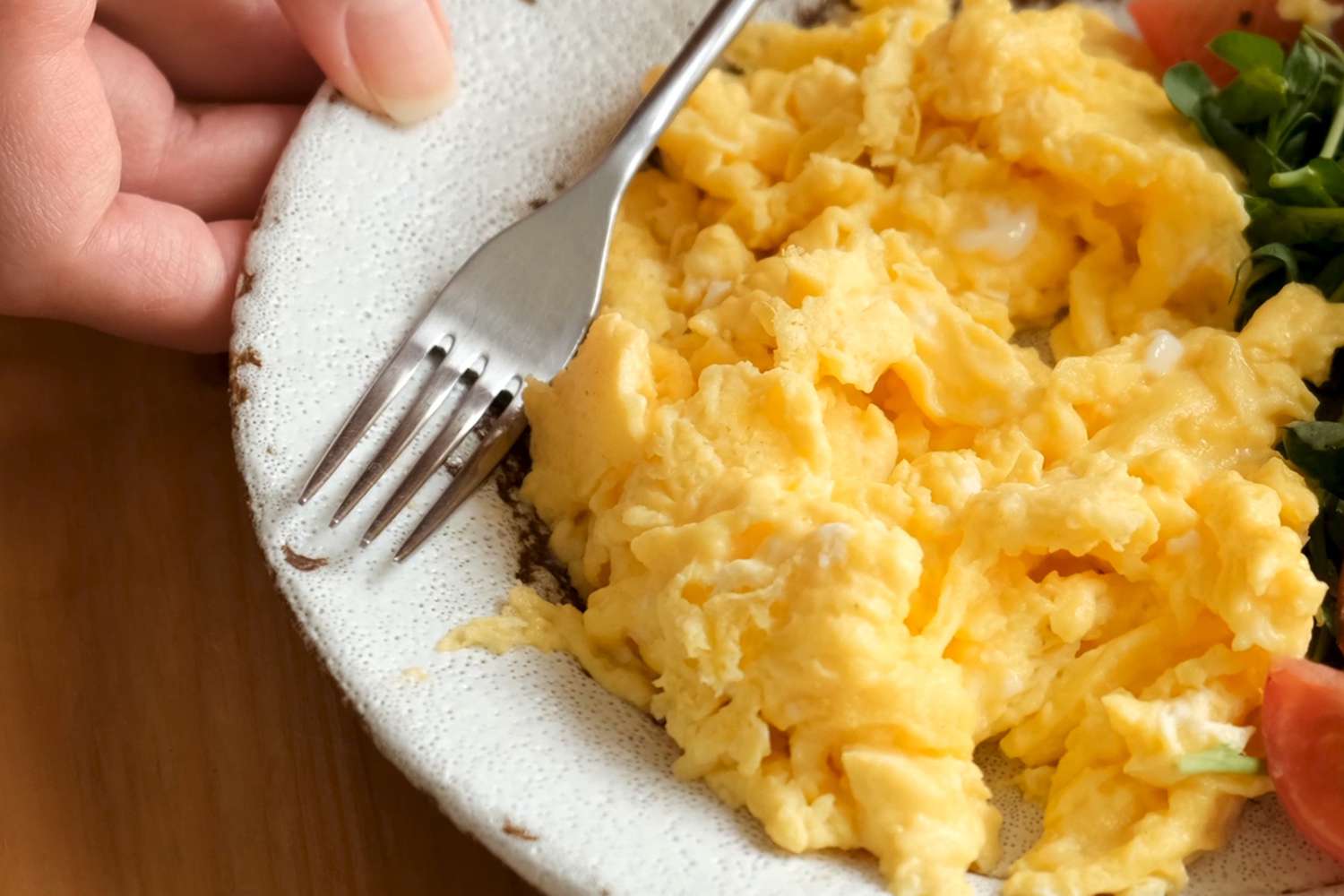 crop of a plate with scrambled eggs and a fork