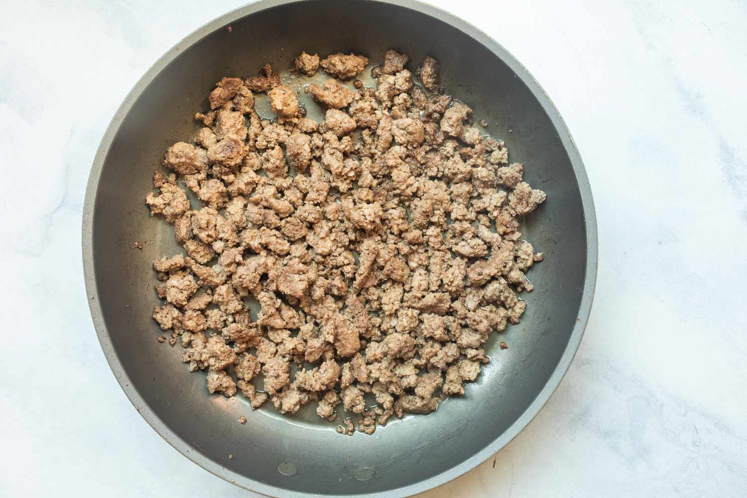 Ground beef cooked in skillet.