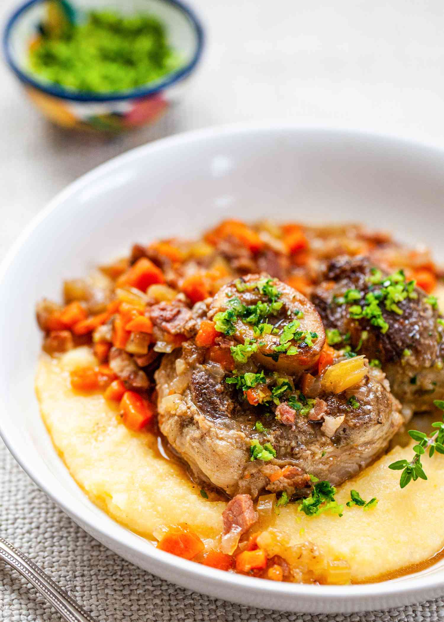 Osso Buco on top of polenta in a white bowl