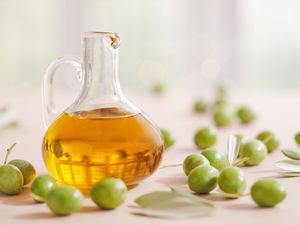 Green olives and olive oil in a glass cruet