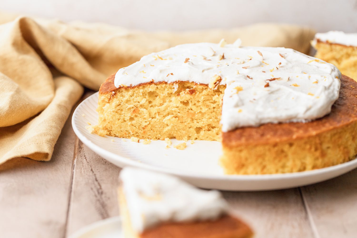 An iced cake made with clementine on a platter with a slice taken out
