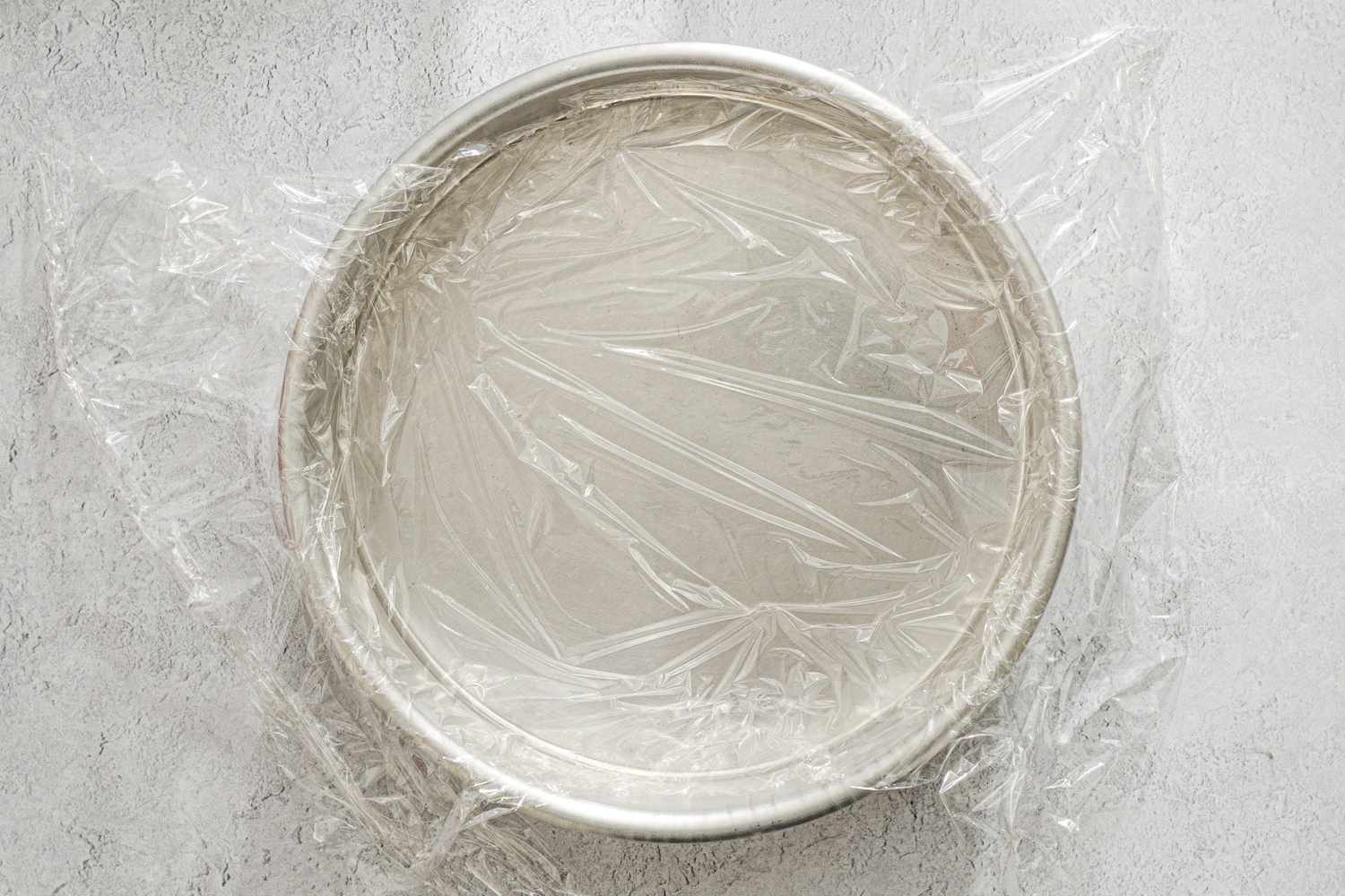 Cake pan lined with plastic wrap.