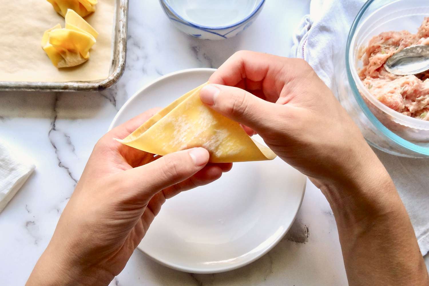 Folding wonton in half to make pork and ginger wontons in chicken soup