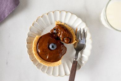 Mini chocolate pudding pie on a white plate with a fork topped with blueberries