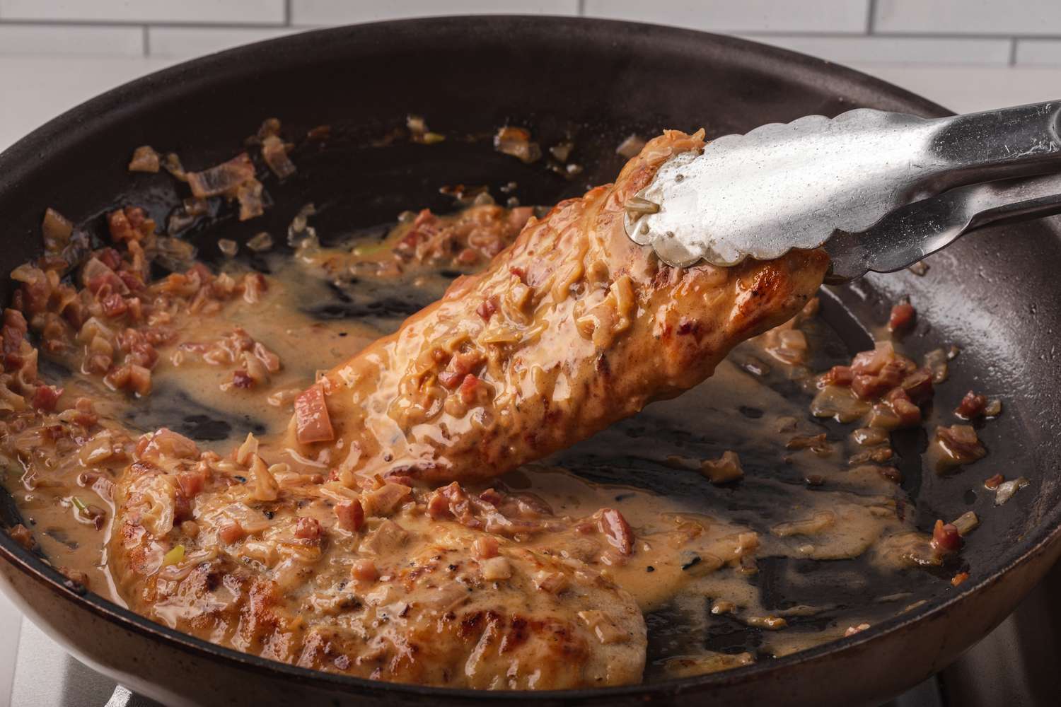 Adding chicken to the sauce for a chicken marsala recipe.