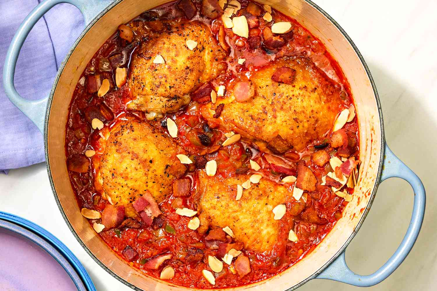 Overhead view of a blue dutch oven of finished Country Captain Chicken recipe on a white background